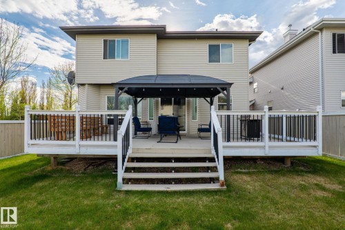 Expansive deck with white railings and black balusters, featuring a covered pergola structure - 3403 23 Nw, Edmonton, AB - Outdoor With Deck Patio Veranda With Exterior