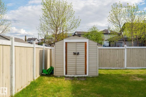 Enclosed backyard with a storage shed, wood fencing, and green lawn - 3403 23 Nw, Edmonton, AB - Outdoor