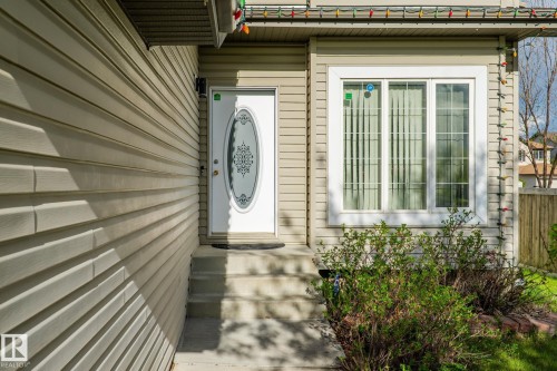 Siding exterior with a decorative glass front door, concrete entry steps, and a multi-pane window - 3403 23 Nw, Edmonton, AB - Outdoor