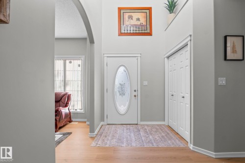 Foyer with vaulted ceilings, wood-finish flooring, and a white front door featuring an oval decorative glass insert - 3403 23 Nw, Edmonton, AB - Indoor Photo Showing Other Room