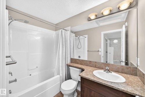 Bathroom featuring a full tub/shower combination with a white surround, a vanity with a brown countertop, an undermount sink, a large mirror, and recessed lighting - 466 Chappelle Drive Sw, Edmonton, AB - Indoor Photo Showing Bathroom