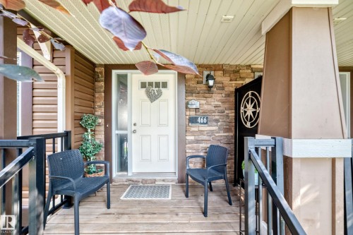 Covered front porch featuring wood-finish flooring, stone accent wall, and a full-light entry door - 466 Chappelle Drive Sw, Edmonton, AB - Outdoor