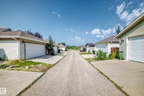 Rear lane access with concrete driveways leading to attached garages, each featuring a pitched shingle roof - 466 Chappelle Drive Sw, Edmonton, AB - Outdoor
