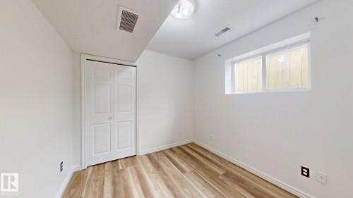 Wood-finish flooring, white walls, double bi-fold closet doors, and recessed window - 2426 33A Street Nw, Edmonton, AB - Indoor Photo Showing Other Room
