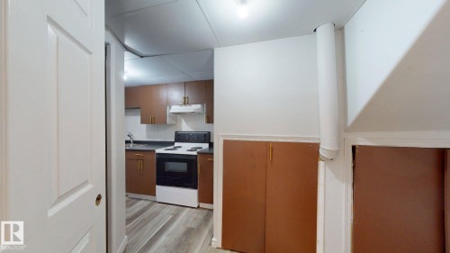 Kitchen featuring wood-finish cabinetry, dark countertops, and a white electric range - 2426 33A Street Nw, Edmonton, AB - Indoor Photo Showing Kitchen