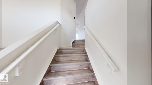 Staircase featuring wood-finish treads, white risers, and a white handrail - 2426 33A Street Nw, Edmonton, AB - Indoor Photo Showing Other Room