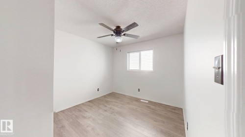 Wood-finish flooring with white walls and a pop-textured ceiling - 2426 33A Street Nw, Edmonton, AB - Indoor Photo Showing Other Room