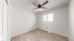 Recessed window with horizontal blinds, wood-finish flooring, ceiling fan with integrated lighting, and a white paneled door - 
