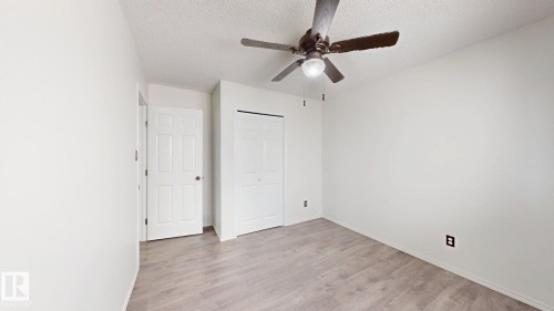 Wood-finish flooring with a ceiling fan light fixture and a multi-panel door - 2426 33A Street Nw, Edmonton, AB - Indoor Photo Showing Other Room