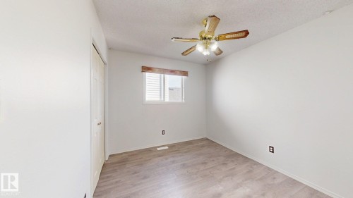 Wood-finish flooring with a ceiling fan light fixture, window with blinds, and white bi-fold closet doors - 2426 33A Street Nw, Edmonton, AB - Indoor Photo Showing Other Room