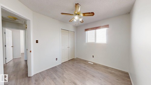 Neutral wall finishes, wood-finish flooring, ceiling fan with integrated lighting, and a window with horizontal blinds - 2426 33A Street Nw, Edmonton, AB - Indoor Photo Showing Other Room