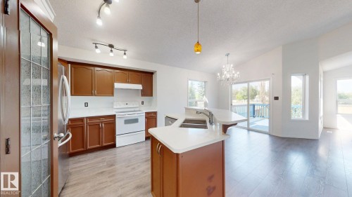 Kitchen featuring wood-finish flooring, wood cabinetry, white countertops, and a built-in range - 2426 33A Street Nw, Edmonton, AB - Indoor Photo Showing Kitchen With Double Sink