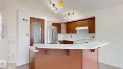 Kitchen featuring wood-finish cabinetry, white countertops, stainless steel refrigerator, and track lighting - 