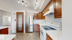 Kitchen featuring wood-finish flooring, white countertops, wood cabinetry, and stainless steel refrigerator - 
