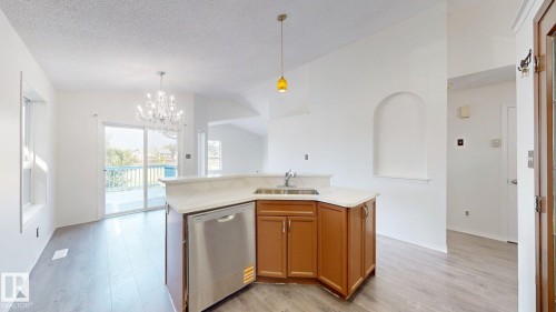 Kitchen featuring wood-finish cabinetry, stainless steel dishwasher, and light-toned countertops - 2426 33A Street Nw, Edmonton, AB - Indoor Photo Showing Kitchen