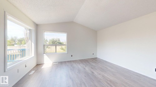 Vaulted ceiling, two windows, light-toned walls, wood-finish flooring, and white trim - 2426 33A Street Nw, Edmonton, AB - Indoor Photo Showing Other Room