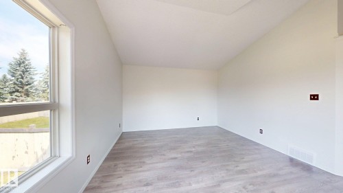 Vaulted ceiling, wood-finish flooring, white walls, and a large window - 2426 33A Street Nw, Edmonton, AB - Indoor Photo Showing Other Room
