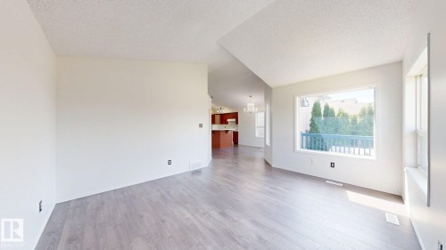 Light wood-finish flooring, vaulted ceiling, white interior walls, and a large window with white trim - 2426 33A Street Nw, Edmonton, AB - Indoor Photo Showing Other Room