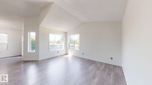 Vaulted ceilings complement the neutral wall finishes and wood-finish flooring - 2426 33A Street Nw, Edmonton, AB - Indoor Photo Showing Other Room