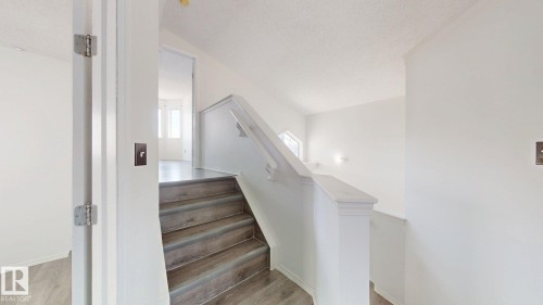 Staircase with wood-finish treads and white risers, featuring a white painted handrail - 2426 33A Street Nw, Edmonton, AB - Indoor Photo Showing Other Room
