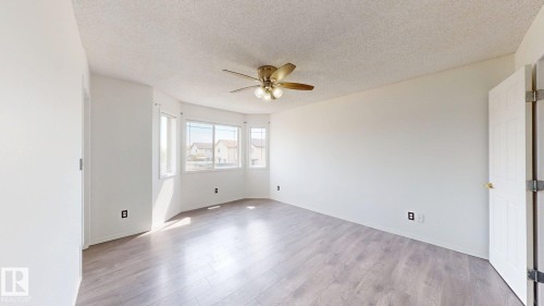 Wood-finish flooring, multiple windows, and a ceiling fan with integrated lighting - 2426 33A Street Nw, Edmonton, AB - Indoor Photo Showing Other Room