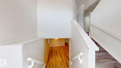 Multi-level interior featuring wood-finish flooring, a staircase with tile risers, and white painted handrails - 2426 33A Street Nw, Edmonton, AB - Indoor Photo Showing Other Room
