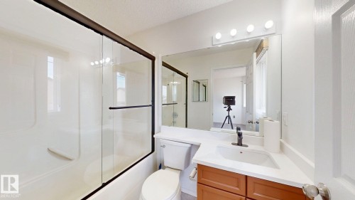 White ceramic bathtub with sliding glass enclosure - 2426 33A Street Nw, Edmonton, AB - Indoor Photo Showing Bathroom