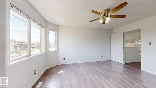 Wood-finish flooring with a ceiling fan light fixture - 2426 33A Street Nw, Edmonton, AB - Indoor Photo Showing Other Room