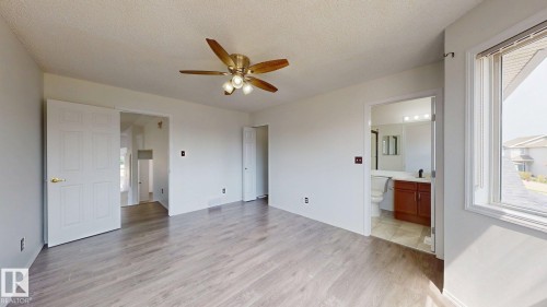 Spacious room featuring wood-finish flooring, a ceiling fan with integrated lighting, and white trim - 2426 33A Street Nw, Edmonton, AB - Indoor Photo Showing Other Room