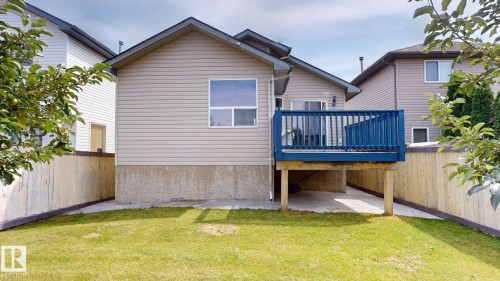 Rear exterior featuring a blue wooden deck, concrete patio, and fenced yard - 2426 33A Street Nw, Edmonton, AB - Outdoor