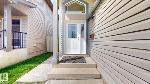 Entryway featuring a white door with transom window, concrete steps, and light-toned siding - 2426 33A Street Nw, Edmonton, AB - Outdoor With Exterior