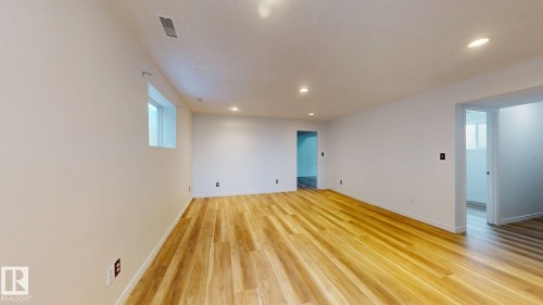 Expansive room featuring wood-finish flooring, recessed lighting, and bright white walls - 2426 33A Street Nw, Edmonton, AB - Indoor Photo Showing Other Room