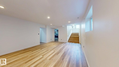 Recessed ceiling lighting, wood-finish flooring, white painted walls, and a wood staircase - 2426 33A Street Nw, Edmonton, AB - Indoor Photo Showing Other Room