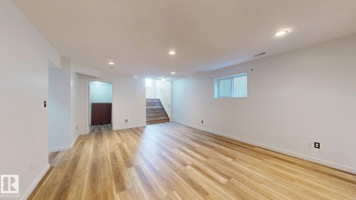 Spacious room featuring wood-finish flooring, recessed lighting, white painted walls, and a window for natural illumination - 2426 33A Street Nw, Edmonton, AB - Indoor Photo Showing Other Room