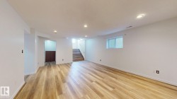 Spacious room featuring wood-finish flooring, recessed lighting, white painted walls, and a window for natural illumination - 