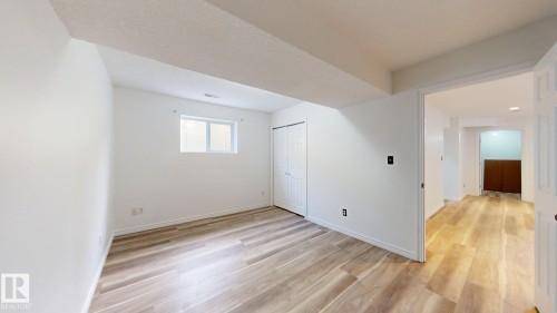 Wood-finish flooring, white walls, and a bi-fold closet door - 2426 33A Street Nw, Edmonton, AB - Indoor Photo Showing Other Room