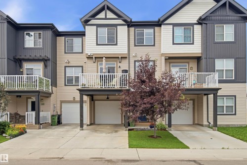 Multi-story townhome exterior featuring contemporary architectural lines, multiple private balconies with white railings, integrated single-car garages, and a paved driveway - 20127 19 Avenue Nw, Edmonton, AB - Outdoor With Balcony With Facade