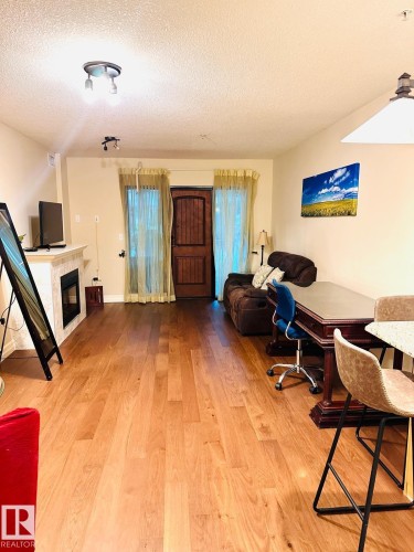 Spacious recreational room featuring hardwood flooring throughout, recessed ceiling lighting, and multiple windows with natural light - #207 10142 111 St Nw, Edmonton, AB - Indoor Photo Showing Other Room With Fireplace