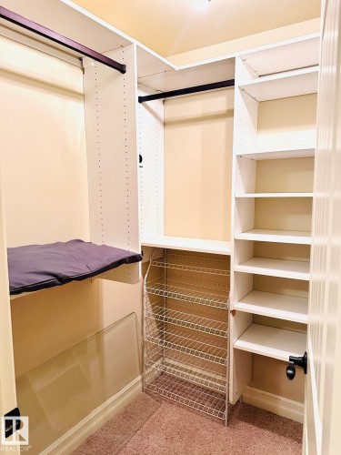 Custom closet system featuring multiple shelves, hanging rods, and a wire rack storage unit - #207 10142 111 St Nw, Edmonton, AB - Indoor With Storage
