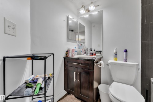 Vanity with dark wood-finish cabinetry, rectangular sink, and wall-mounted mirror - #409 11804 22 Av Sw, Edmonton, AB - Indoor Photo Showing Bathroom