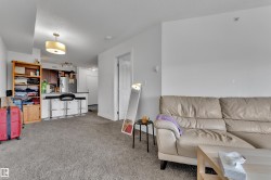 Open-concept living area featuring a kitchen with a breakfast bar, stainless steel refrigerator, and dark wood-finish cabinetry - 