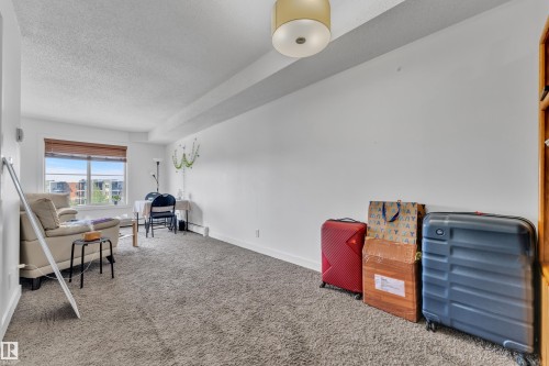 Carpeted flooring throughout, neutral wall finishes, and a window with blinds - #409 11804 22 Av Sw, Edmonton, AB - Indoor