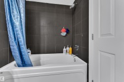 White tub and shower combination with dark tile surround and chrome fixtures - 