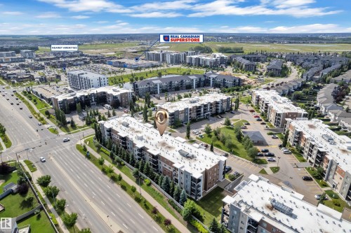Aerial perspective showcasing multi-story residential buildings, surface parking areas, and surrounding roadways - #409 11804 22 Av Sw, Edmonton, AB - Outdoor With View