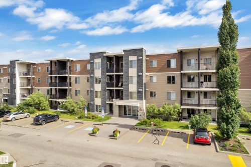Contemporary building exterior with multi-level balconies, stone facade accents, and a dedicated parking area - #409 11804 22 Av Sw, Edmonton, AB - Outdoor With Balcony With Facade