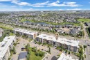 Aerial perspective showcasing a multi-story residential building within a developed community, featuring surface parking, green spaces, and surrounding residential areas with ponds - #409 11804 22 Av Sw, Edmonton, AB  - Outdoor With View 