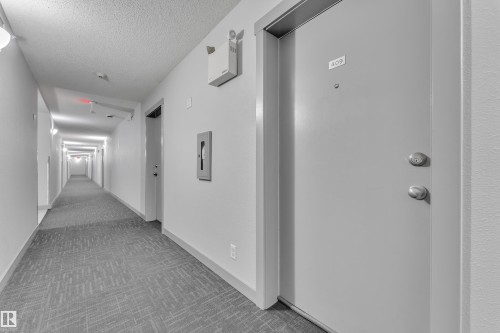 Corridor with modern patterned carpet, recessed wall lighting, and apartment entry doors - #409 11804 22 Av Sw, Edmonton, AB - Indoor Photo Showing Other Room