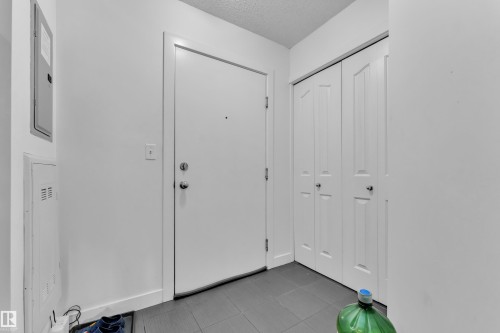 Entryway featuring dark tile flooring, a white solid-core door with chrome hardware, and white bi-fold closet doors - #409 11804 22 Av Sw, Edmonton, AB - Indoor Photo Showing Other Room