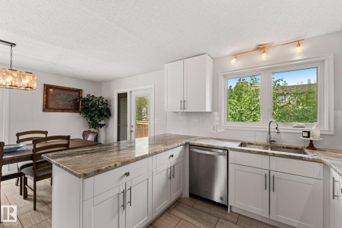 Kitchen featuring light cabinetry, granite countertops, stainless steel dishwasher, undermount sink, and a white subway tile backsplash - 34 Stirling Road Nw, Edmonton, AB - Indoor Photo Showing Kitchen With Double Sink