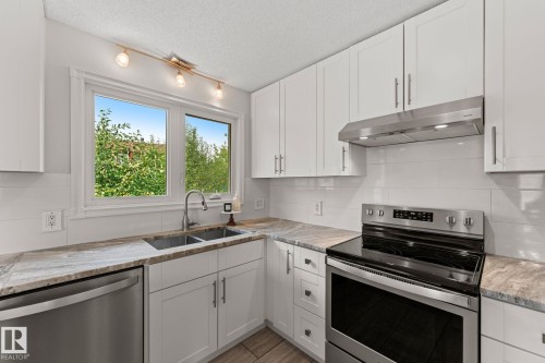 Modern kitchen featuring white shaker cabinetry, stainless steel appliances, granite countertops, and a subway tile backsplash - 34 Stirling Road Nw, Edmonton, AB - Indoor Photo Showing Kitchen With Double Sink